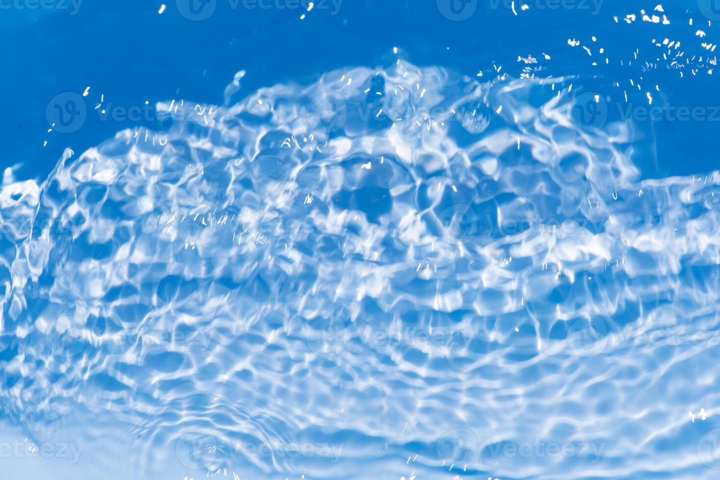 Bluewater waves on the surface ripples blurred. Defocus blurred transparent blue colored clear calm water surface texture with splash and bubbles. Water waves with shining pattern texture background. photo