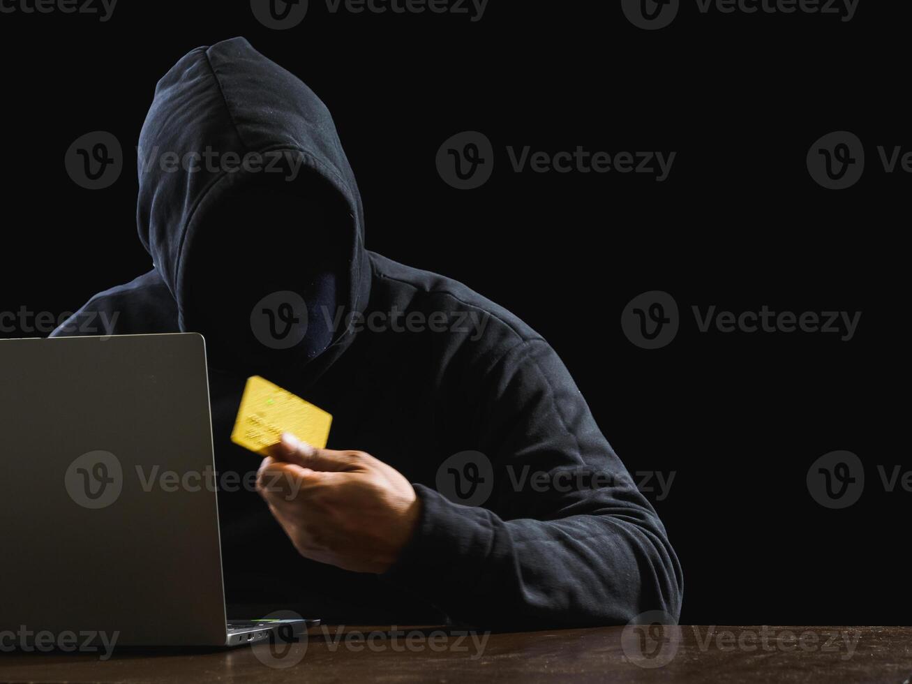 Portrait hacker spy man one person in black hoodie sitting on table looking computer laptop used login password attack security to data digital internet network system night dark background copy space photo