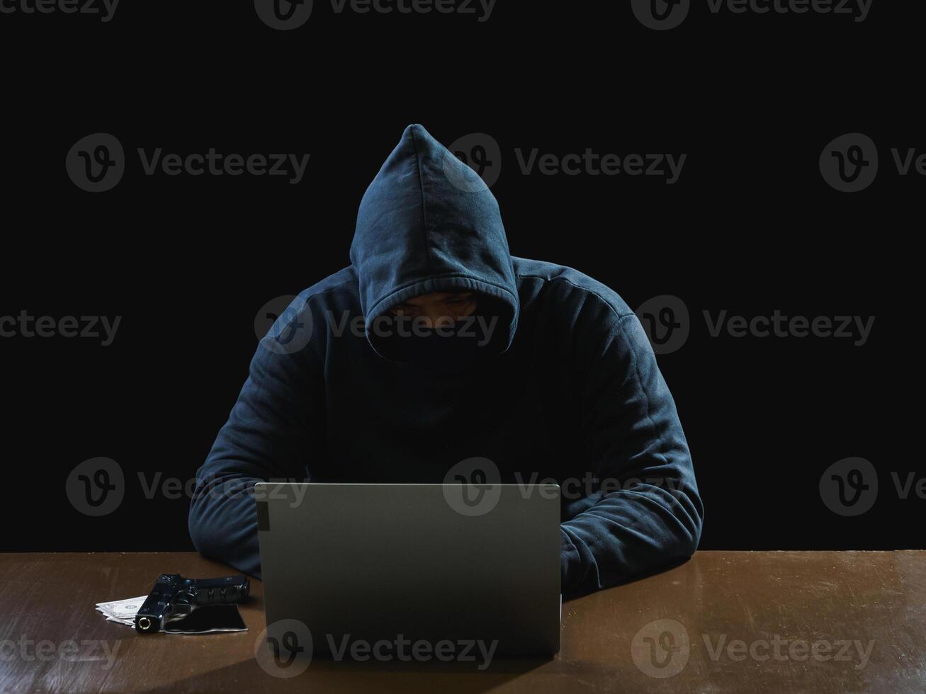 Portrait hacker spy man one person in black hoodie sitting on table looking computer laptop used login password attack security to data digital internet network system night dark background copy space photo