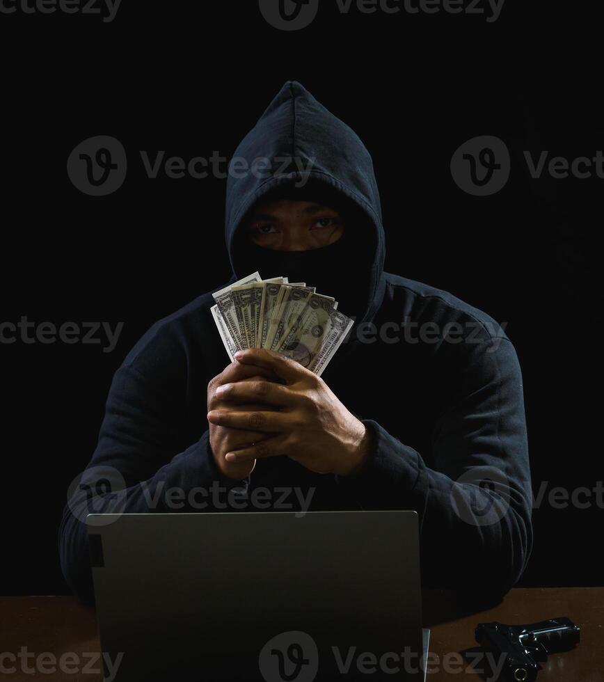 Portrait hacker spy man one person in black hoodie sitting on table looking computer laptop used login password attack security to data digital internet network system night dark background copy space photo