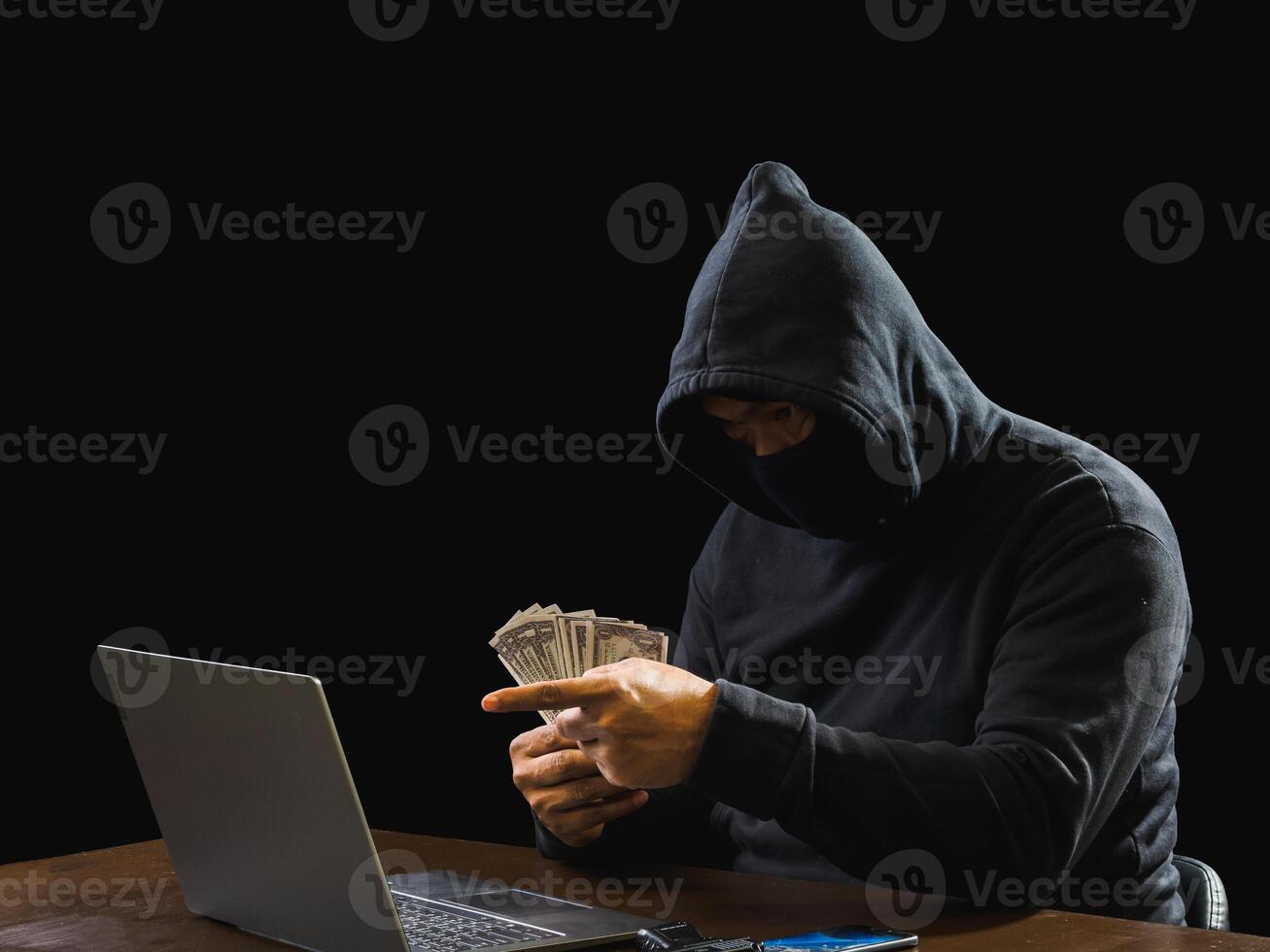 Portrait hacker spy man one person in black hoodie sitting on table looking computer laptop used login password attack security to data digital internet network system night dark background copy space photo