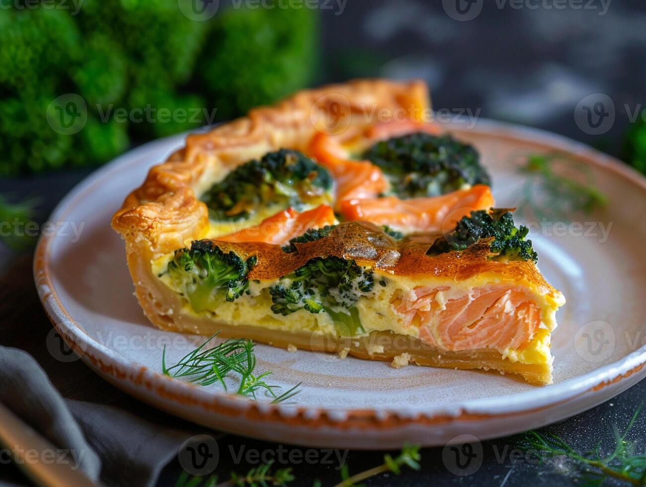 A piece of quiche with salmon and broccoli on a ceramic plate. Puff pastry. Appetizing aesthetic macro photo