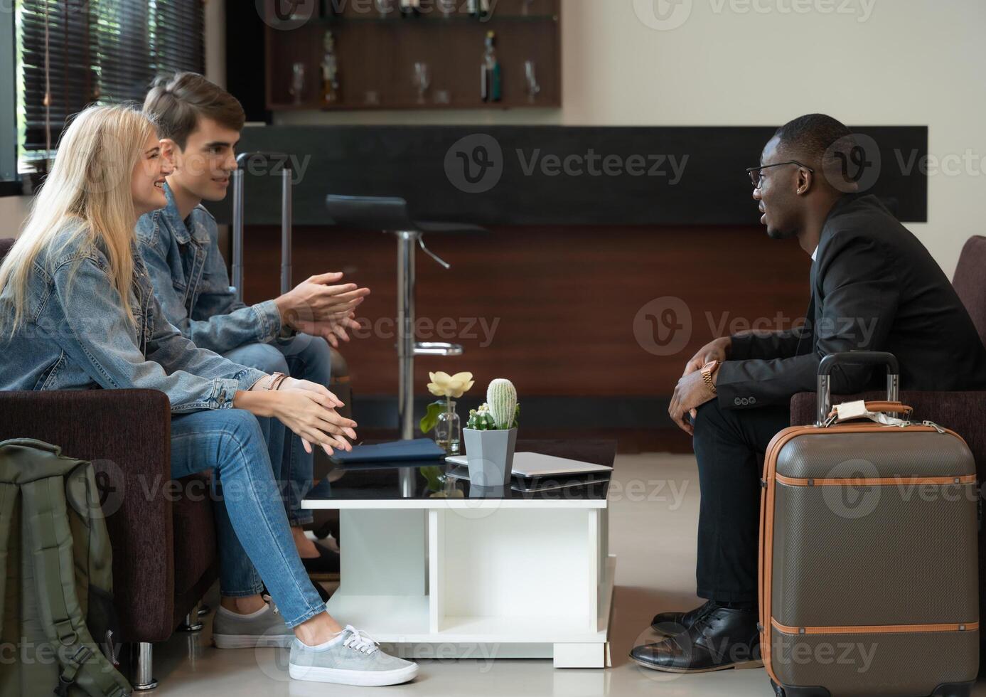Smiling diverse travelers sitting and talking in airport lounge photo