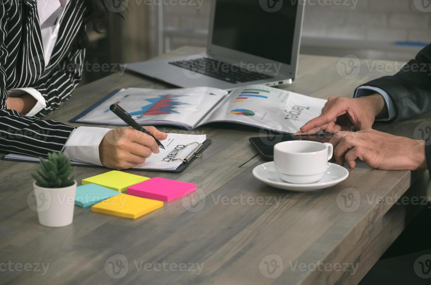 Businesswoman signing business contract while businessman using tablet at office photo