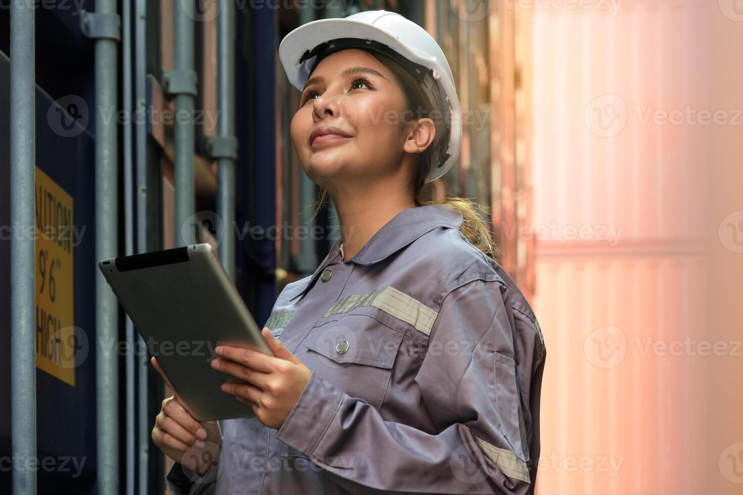 felicidad hembra ingeniero trabajando a internacional Envío carga patio trasero. mujer en uniforme utilizando digital tableta mientras mirando a envase para inspección cargando información foto