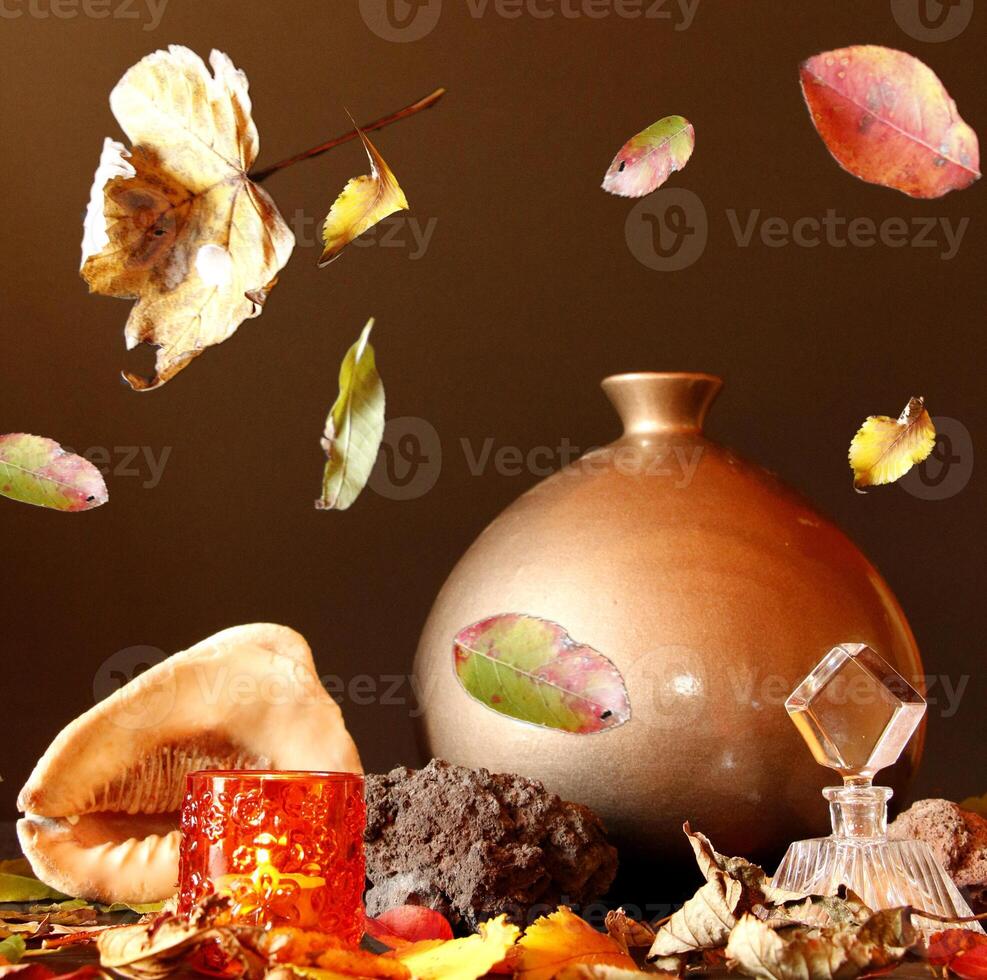 still life of a vase with autumn leaves, shell, candle, perfume bottle photo