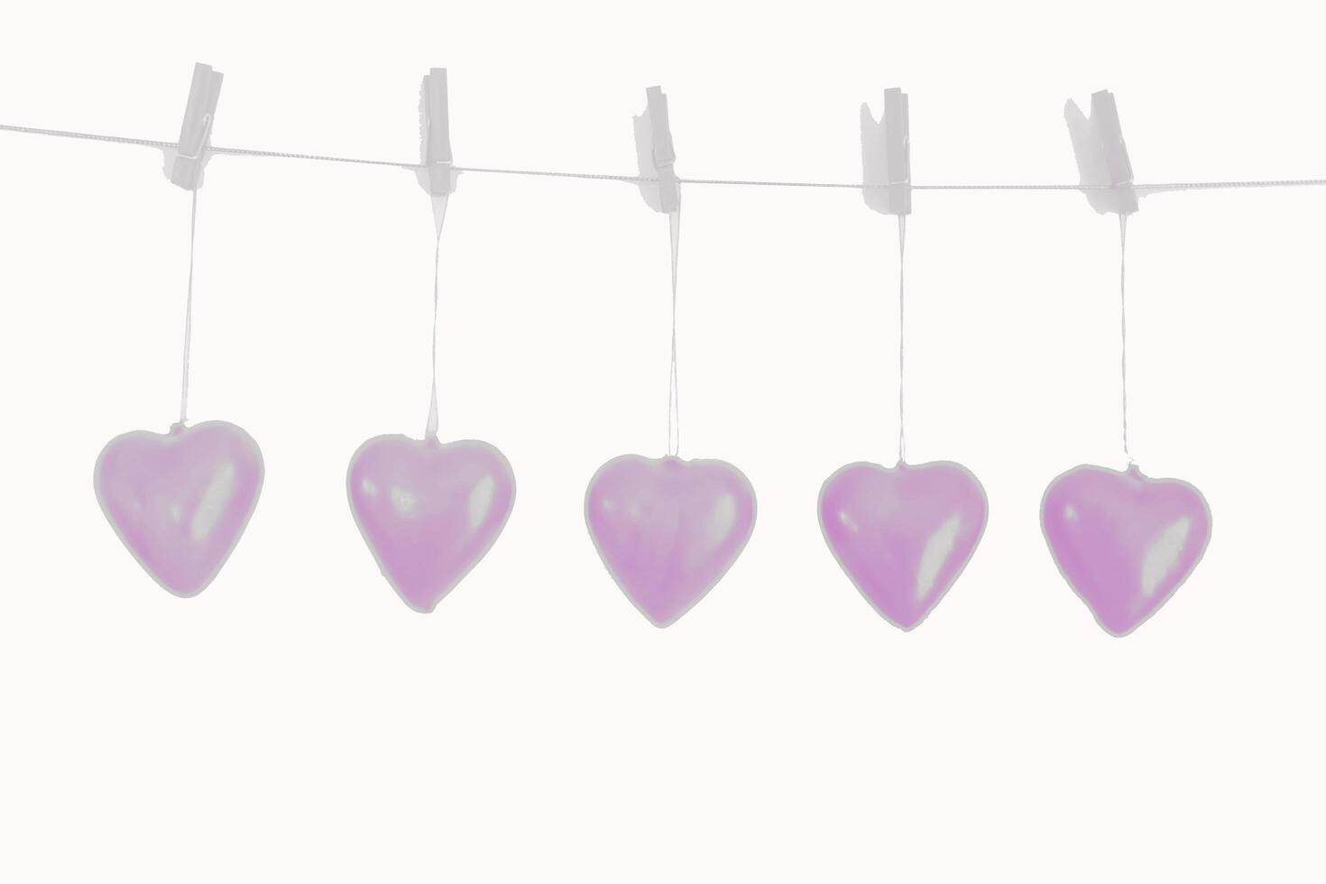 five purple hearts hang from a line with pegs photo