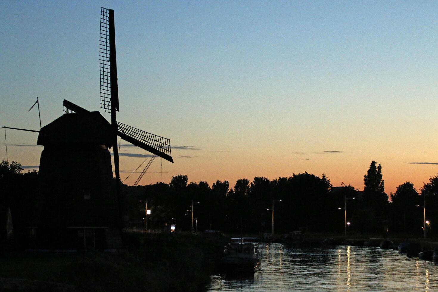 puesta de sol en un holandés paisaje, molino y canal foto