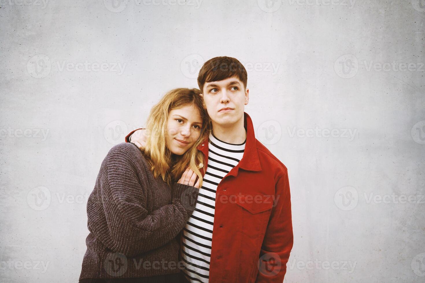 young affectionate couple against concrete wall photo