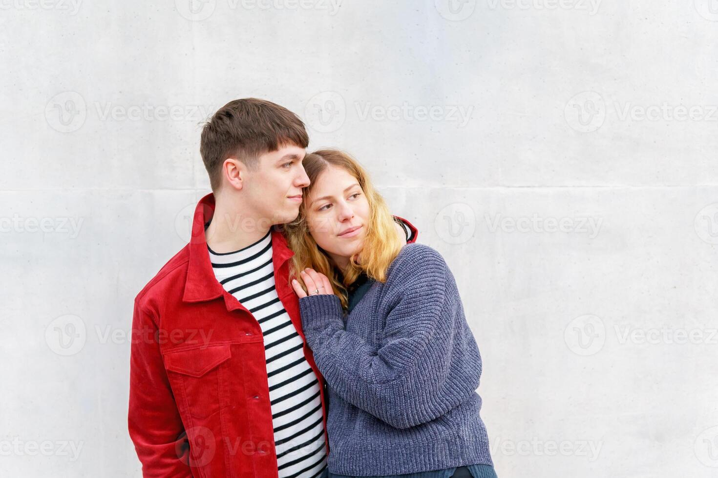 young affectionate couple standing in front of concrete wall photo