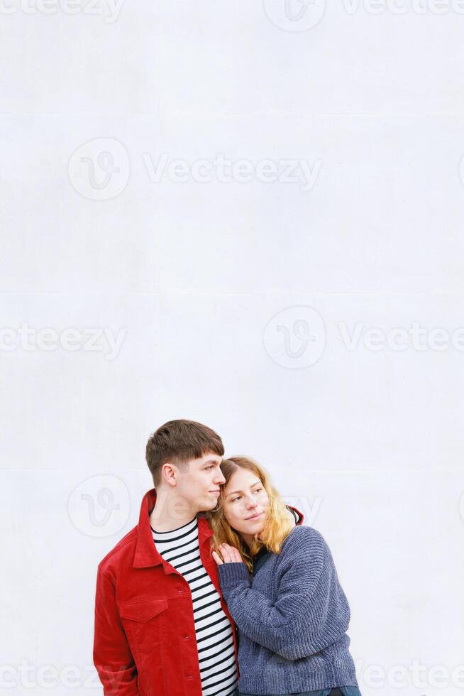 young affectionate couple standing in front of concrete wall photo