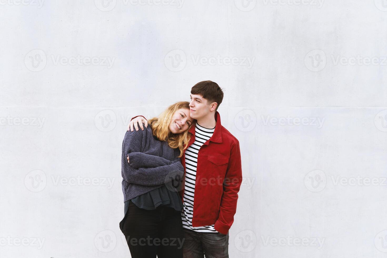 young affectionate couple standing in front of concrete wall photo