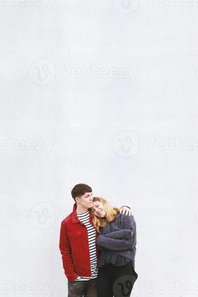 young affectionate couple standing in front of concrete wall photo