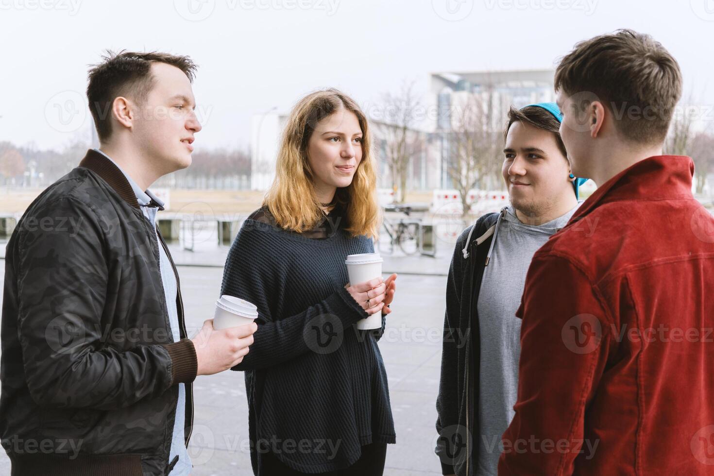 group of teenage friends having a conversation while standing together on city street photo