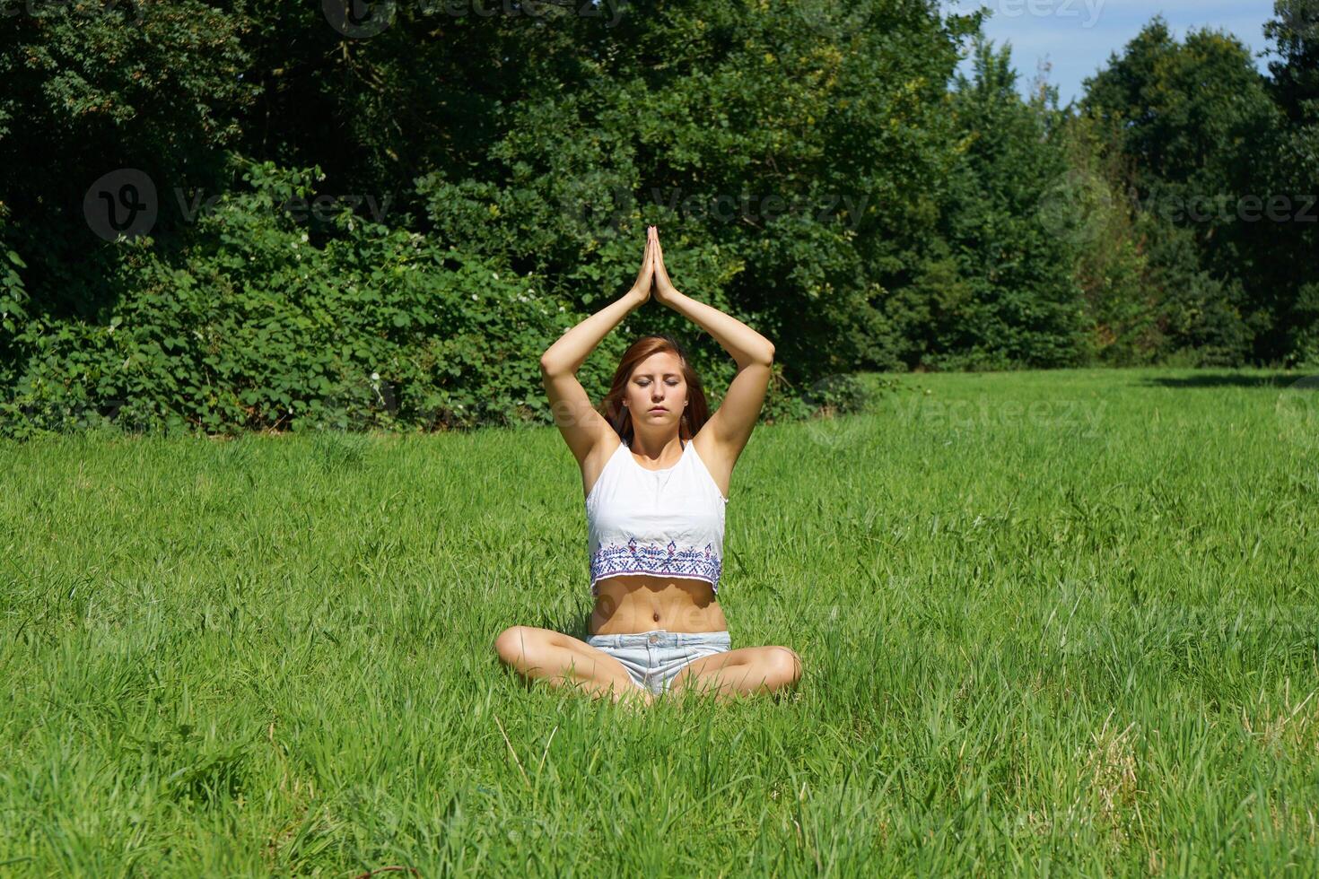 young woman practicing yoga meditation outdoors photo