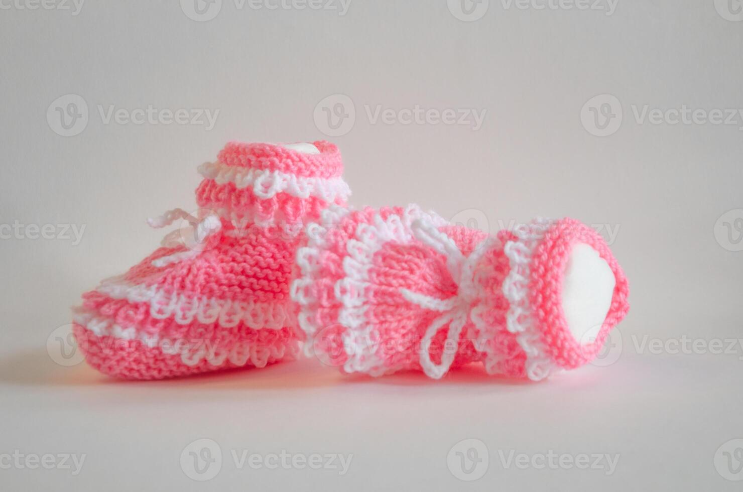 Pink knitted baby booties socks on white background photo