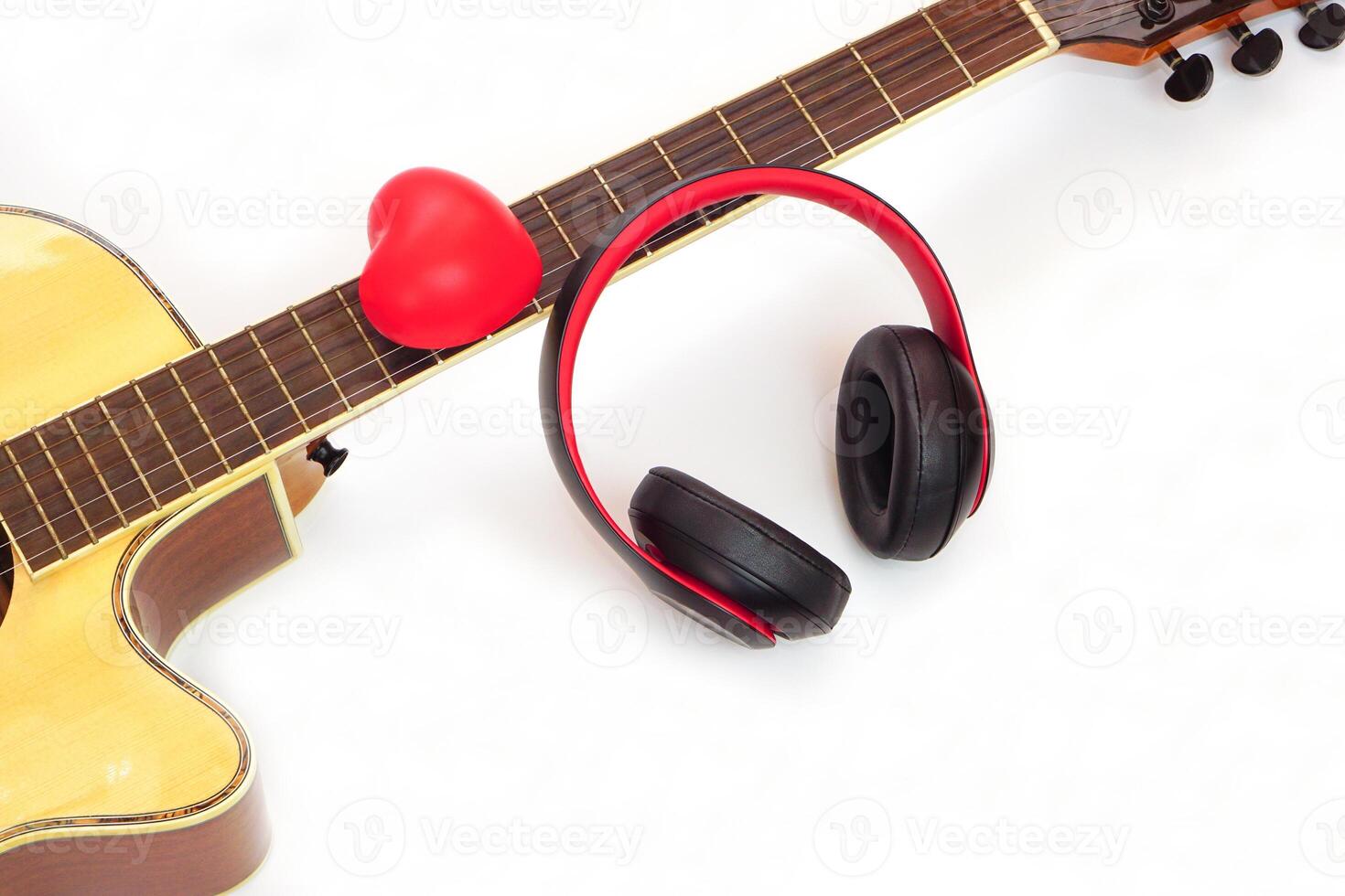 Acoustic guitar, headphones and red heart on a white background. Love, entertainment and music concept. photo