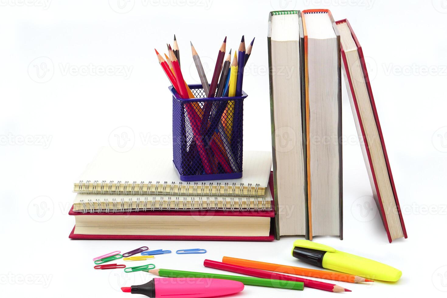 Crayon or colored pencils in box with side stack of books and school supplies on with background. Learning, study and office equipment concept. photo