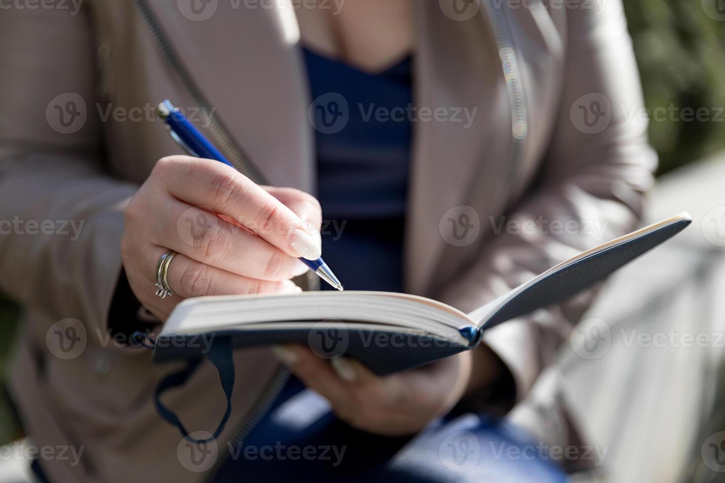 The woman holds up a notepad and pen. She is making notes in her weekly book photo