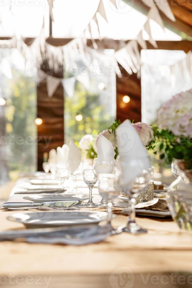 A long festive table decorated with white flowers and greenery. photo