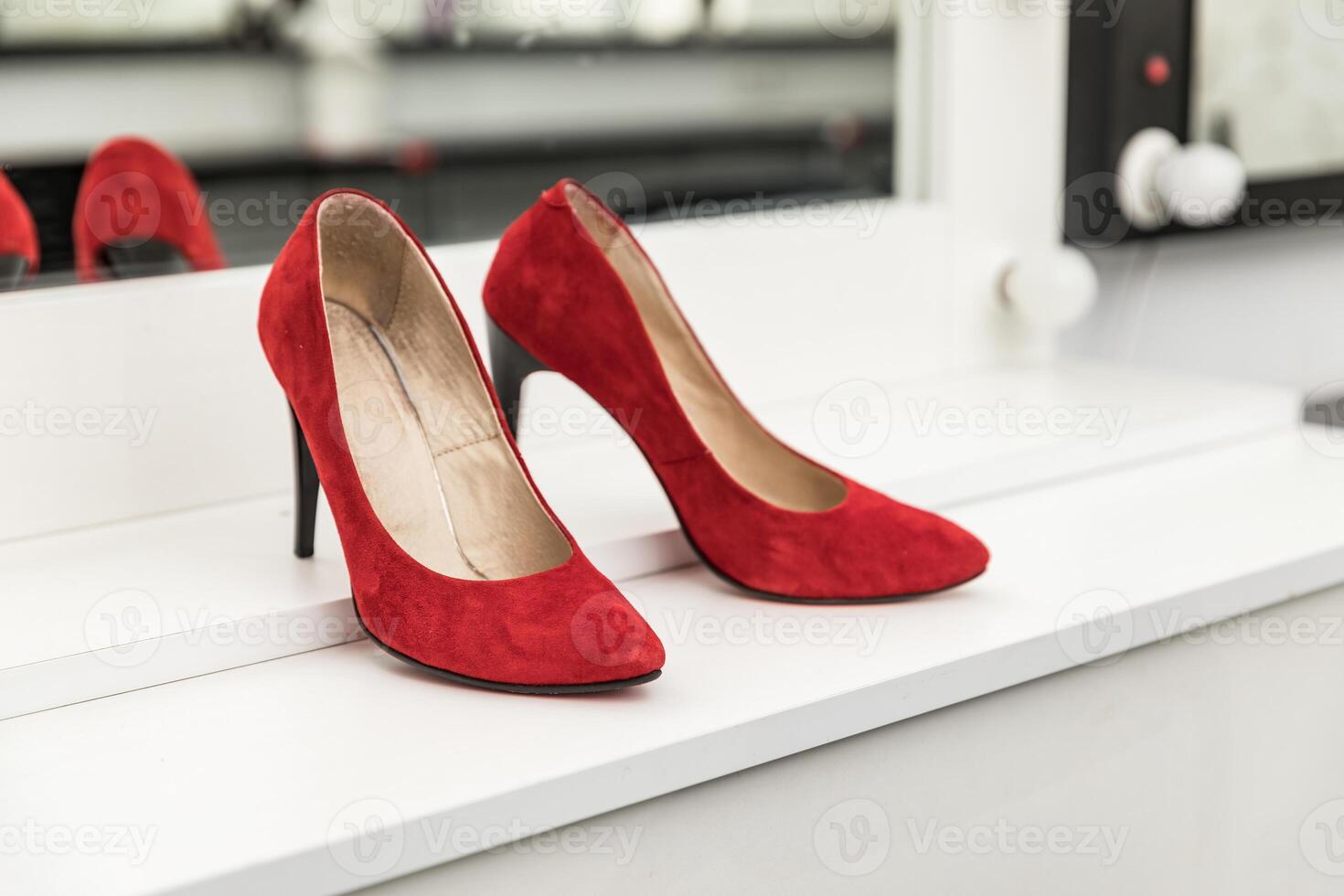 Red suede not new shoes on a white table for makeup photo