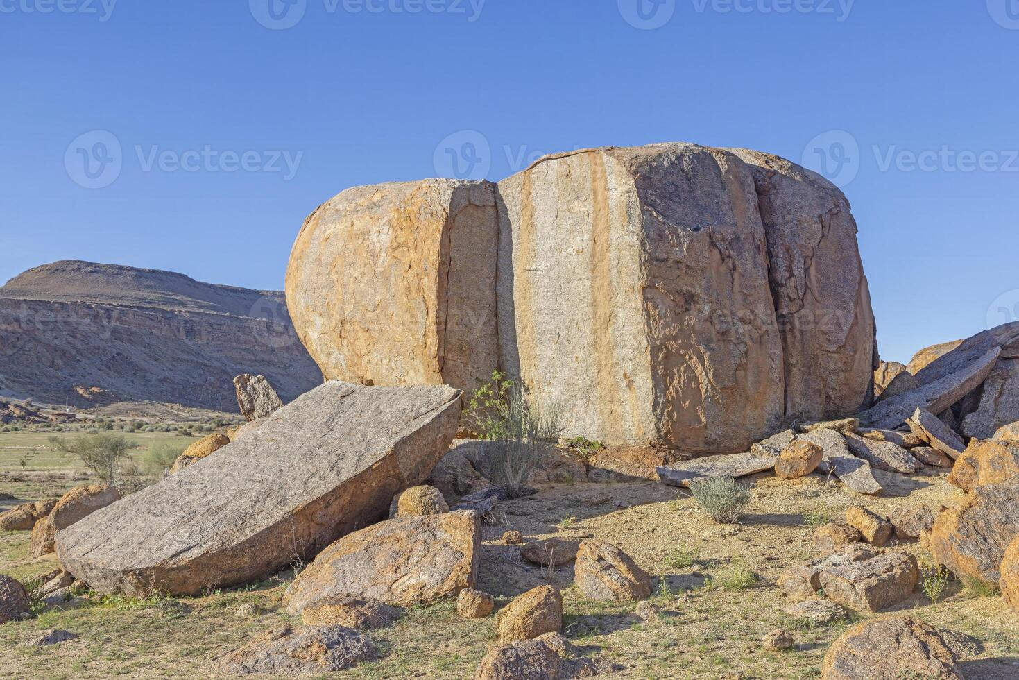 Giant split boulder in the south Namibian desert landscape under a clear blue sky photo