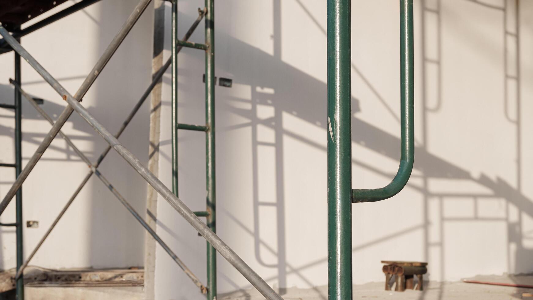 Focus at green scaffolding with blurred light and shadow on concrete wall surface inside of house construction site photo