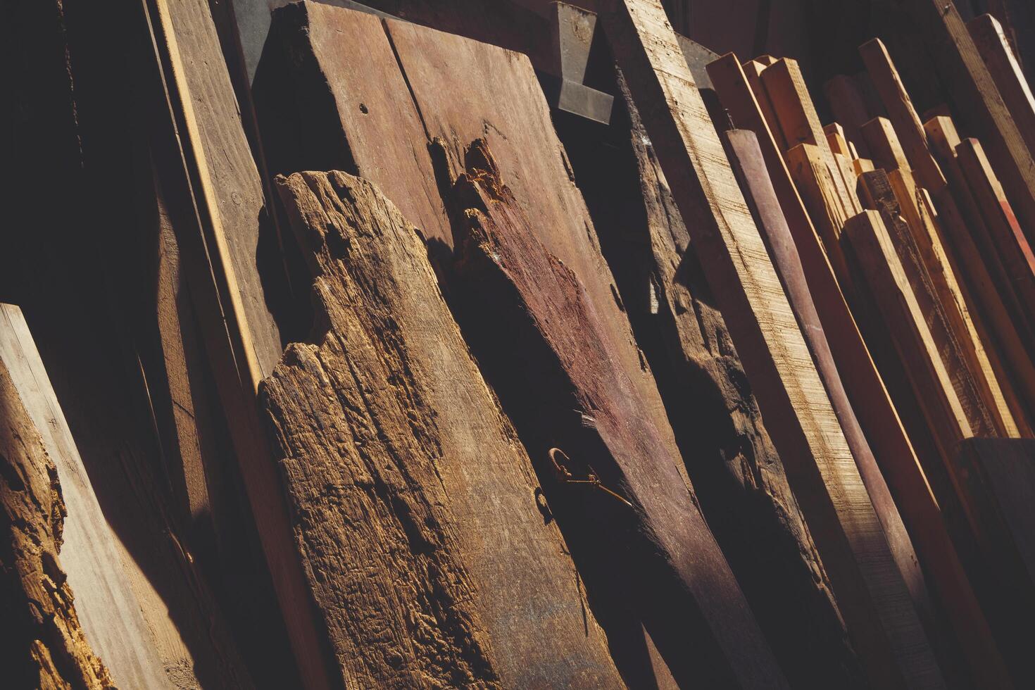 Various of the old remaining wooden material used leaning against the wall in storage room with light and shadow on surface, reuse and recycling concept photo