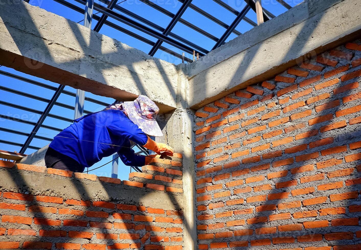 Female bricklayer is working to build brick wall structure in house construction site photo