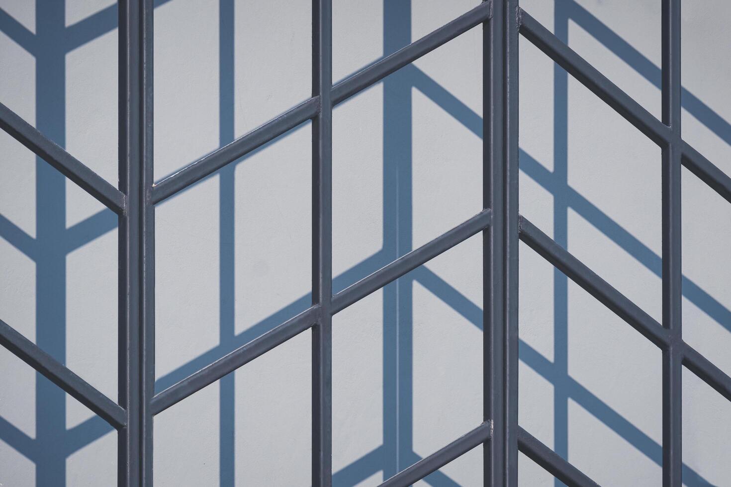 Sunlight and shadow on surface of black steel fence decoration outside of gray building wall in industrial loft style photo