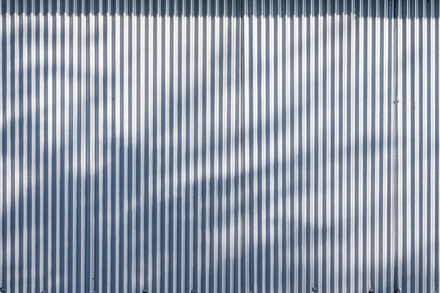 Corrugated zinc fence wall background with sunlight and leaves shadow on surface photo