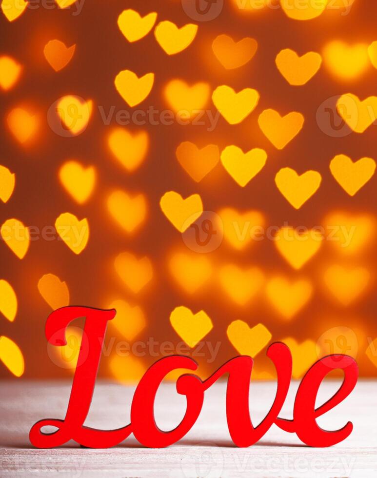 the inscription Love on a wooden background with beautiful hearts made of lights on a blurred background photo