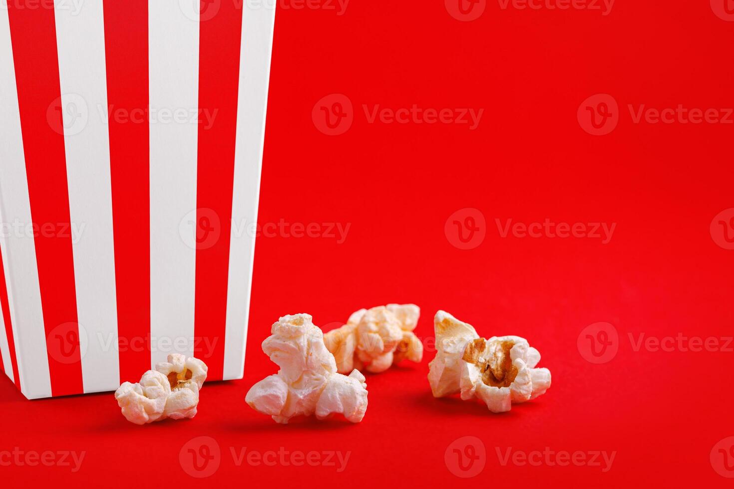 Glass with popcorn on a red background photo