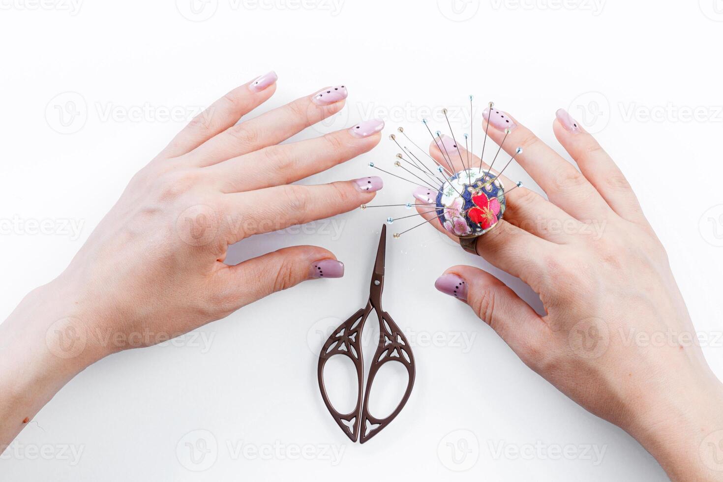 a ring with a small pillow for needles on a hand and scissors on a white background photo