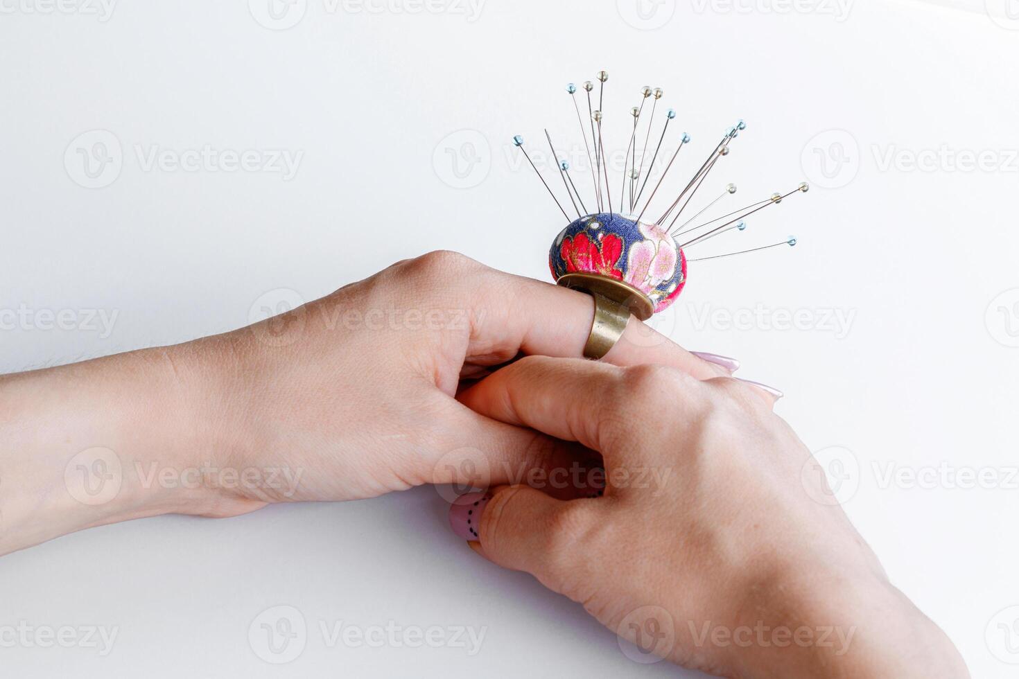 a ring with a small pillow for needles on a hand on a white background photo