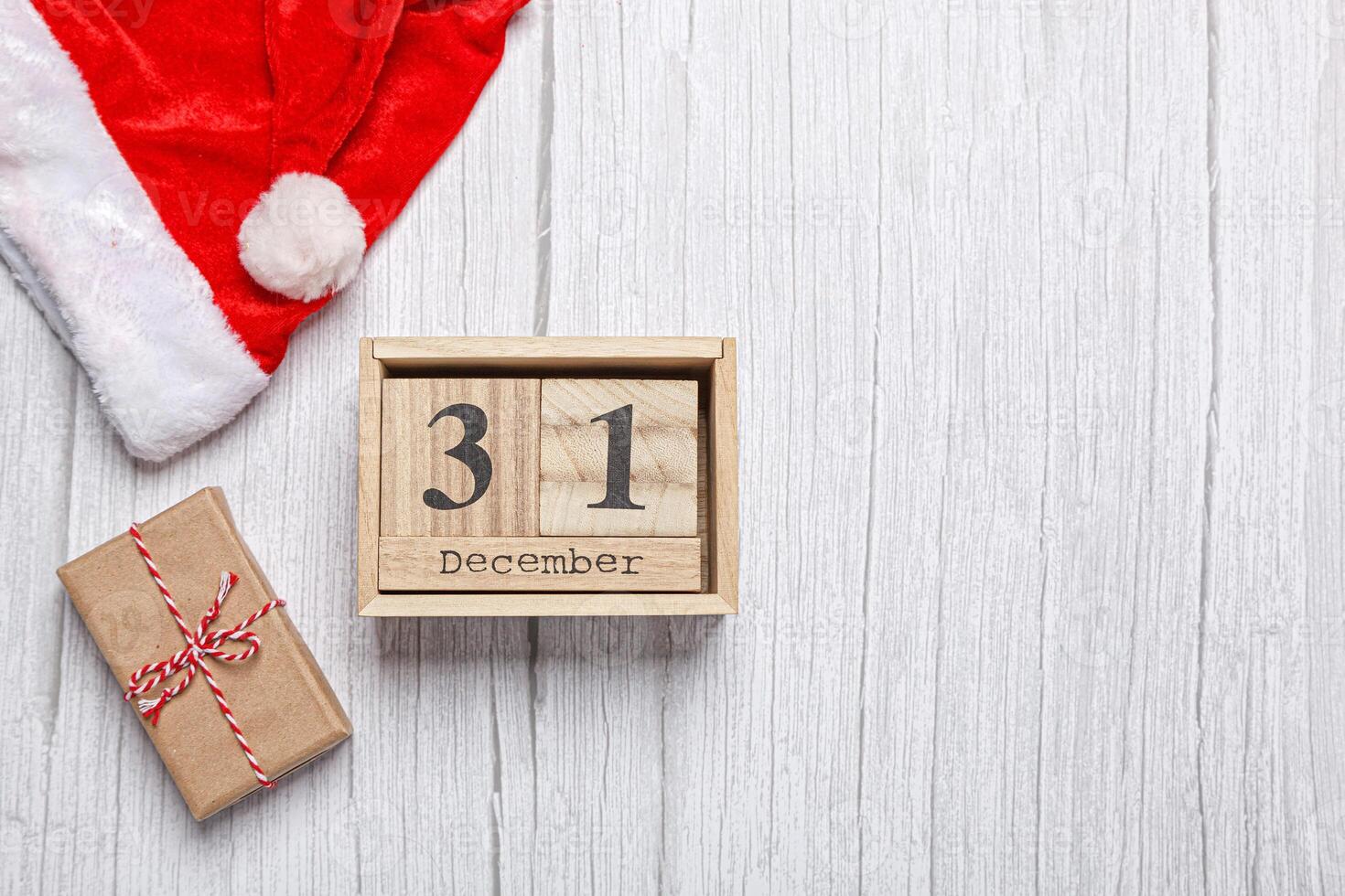 christmas hat, gift and wooden calendar 31 december on a wooden background photo