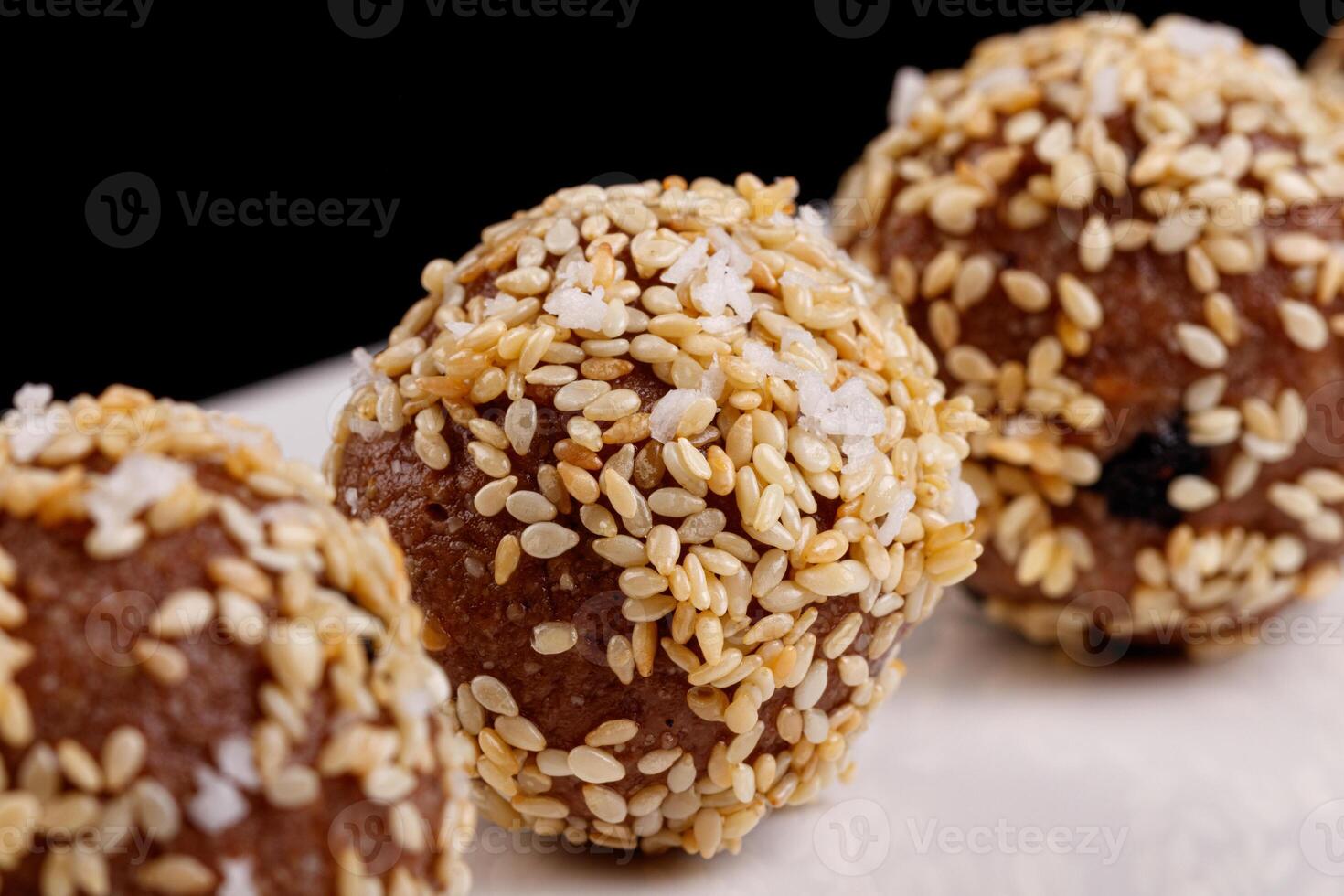 Beautiful candies with sesame seeds on a white plate on a black background photo