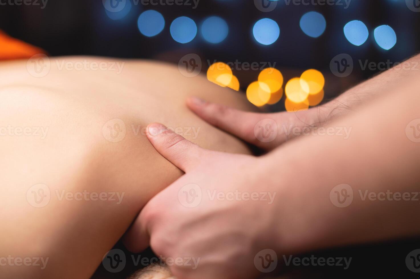 Male hands giving a trapezius muscle massage to a young girl in a professional massage room. photo