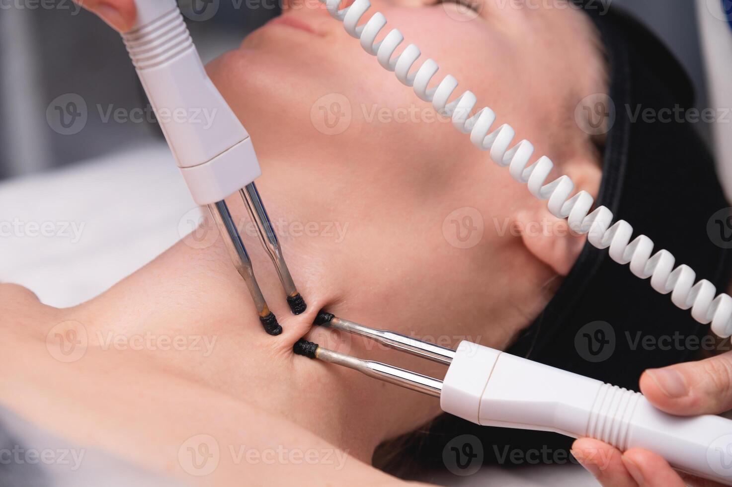 Close-up of a woman receiving an electric neck massage with equipment in a beauty salon. Used for therapy with a multifunctional electro massage device photo