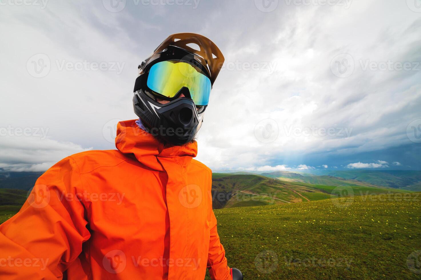 Portrait of a racer in full protection of a full face mask on a bicycle or motorcycle in the summer mountains. The concept of attracting youth to outdoor sports photo