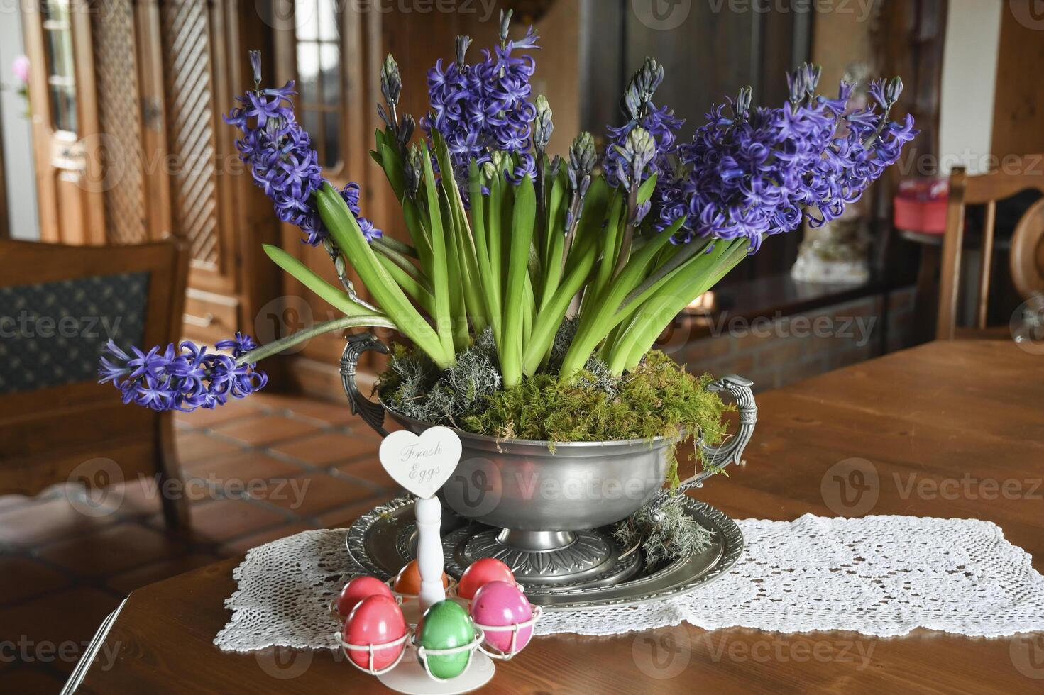 large pewter vase with purple hyacinths on a table in the hall in a rustic style photo