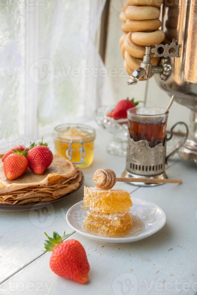 todavía vida en el ruso tradicion para maslenitsa, panqueques con miel y fresas, té desde un Samovar con Bagels foto