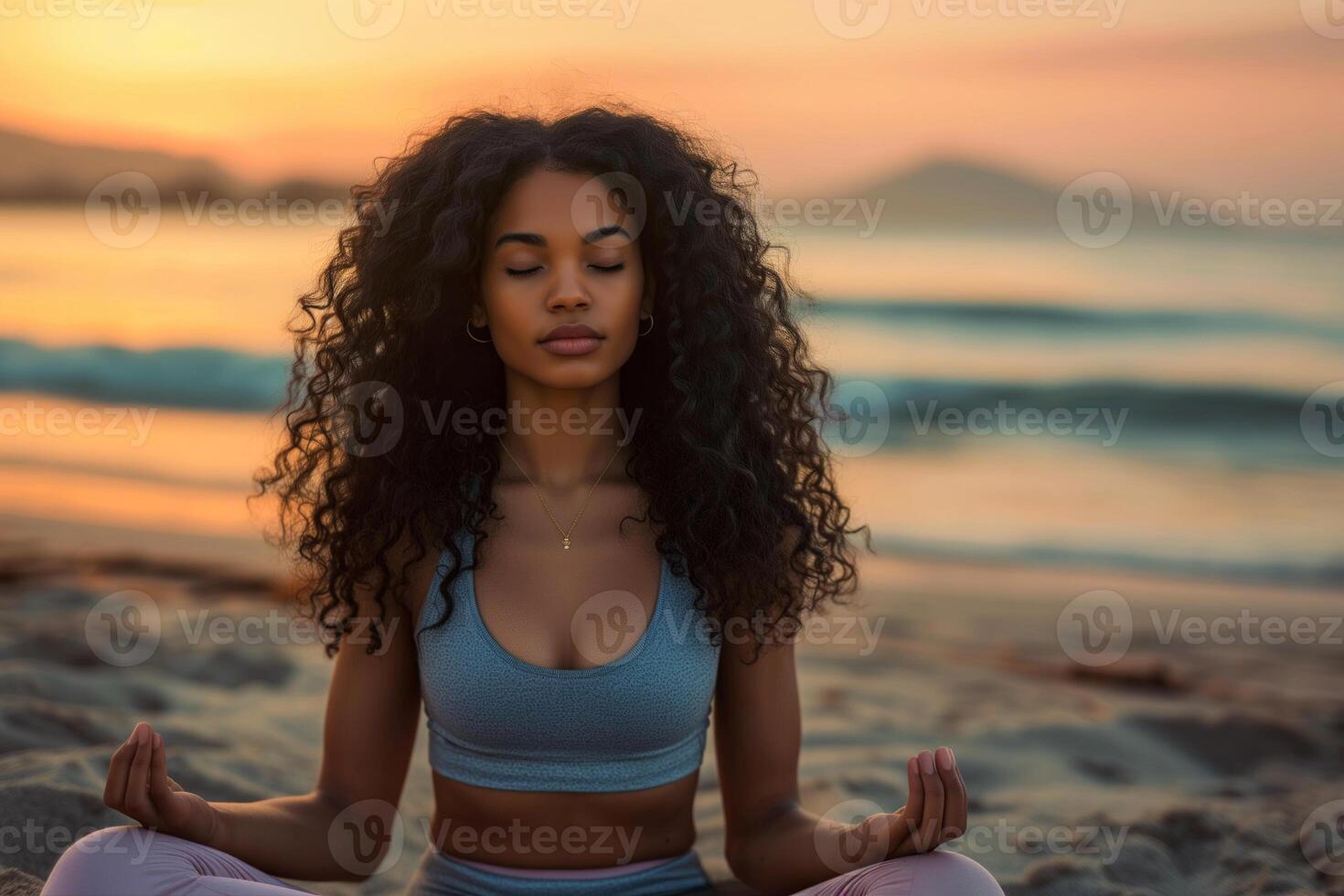 A young black woman with long curly hair doing yoga on the beach photo