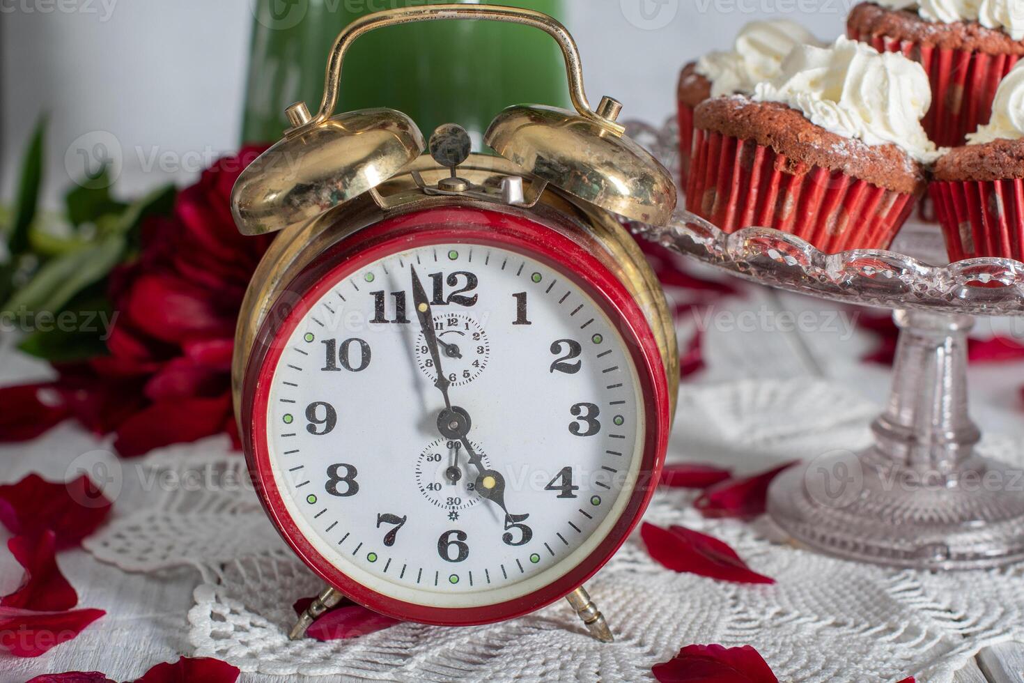 still life in English style with scarlet peonies and red velvet cupcakes with on a platter,tea time on red antique clock photo