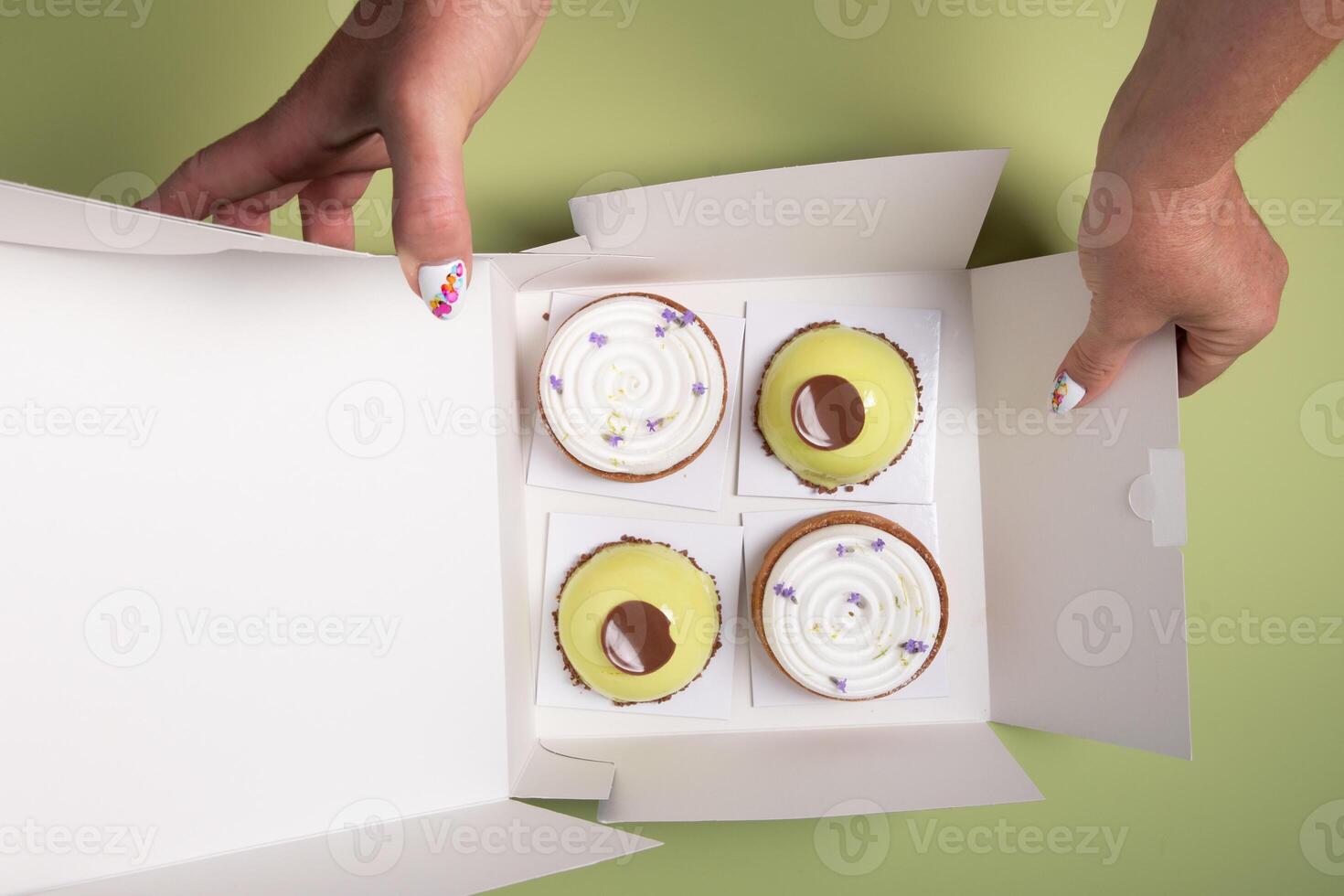 female hands open a box with different cakes dessert home delivery photo