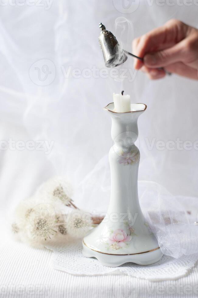 mujer extingue un vela con un plata fuego extintor, todavía vida con un antiguo porcelana candelero foto
