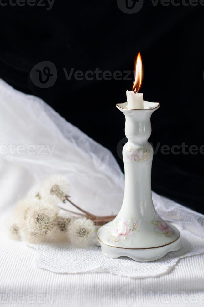 Still life with an antique porcelain candlestick and burning candle on black and white background,loss and condolences photo