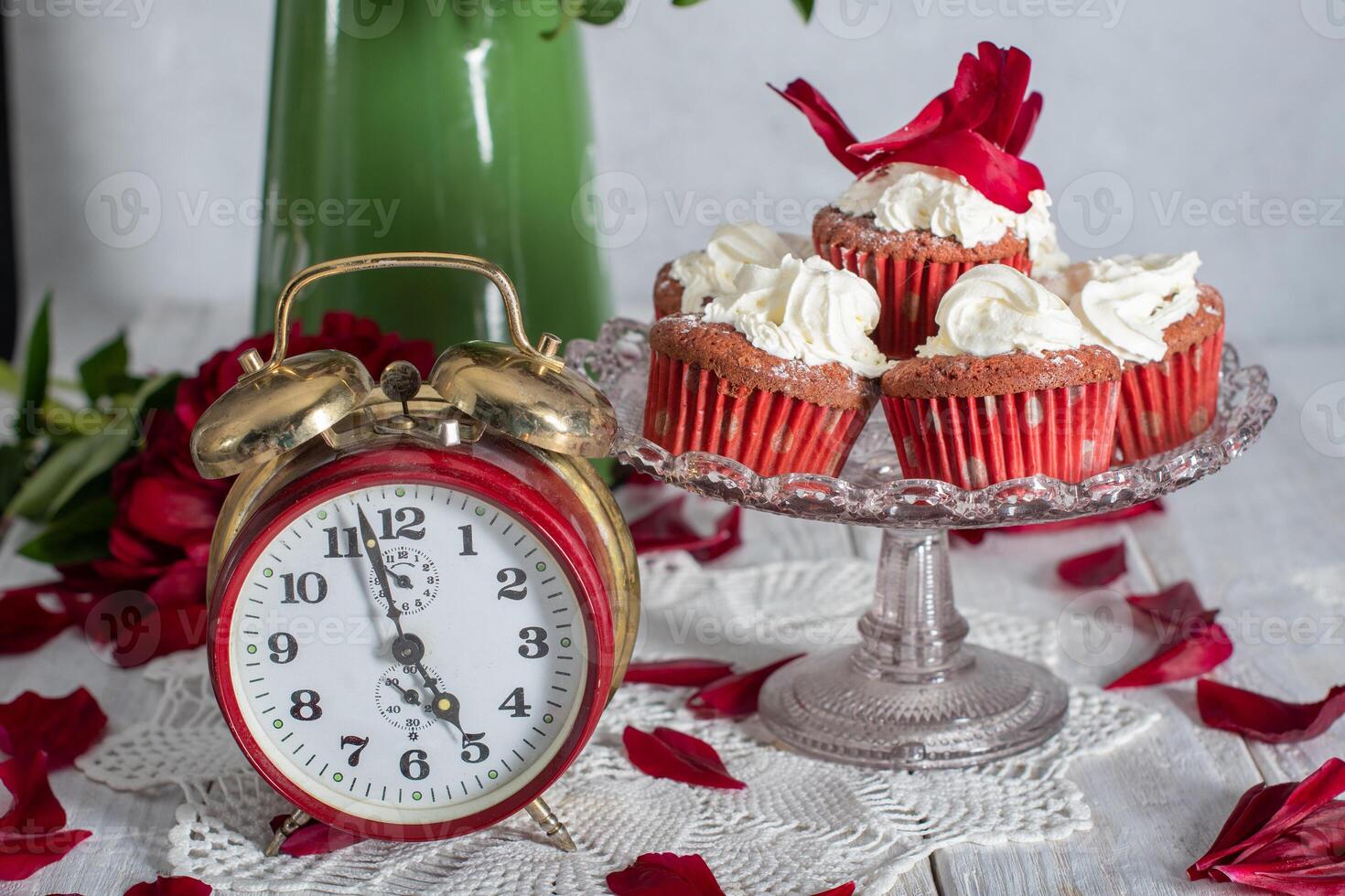 still life in English style with scarlet peonies and red velvet cupcakes with on a platter,tea time on red antique clock photo