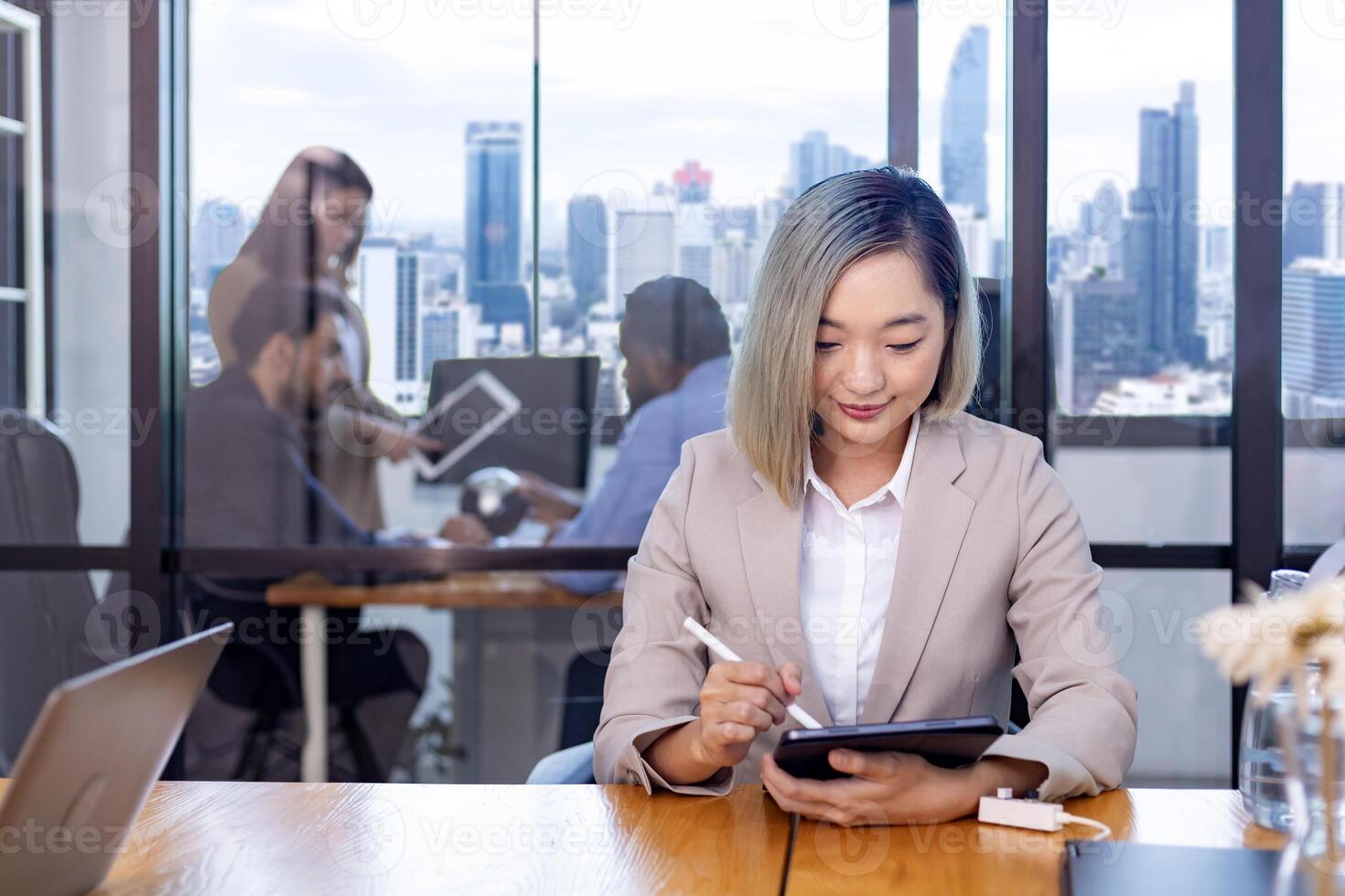 Portrait of Asian business CEO woman is working in office at the table with digital tablet and showing statistic chart showing annual report and skyscraper background photo