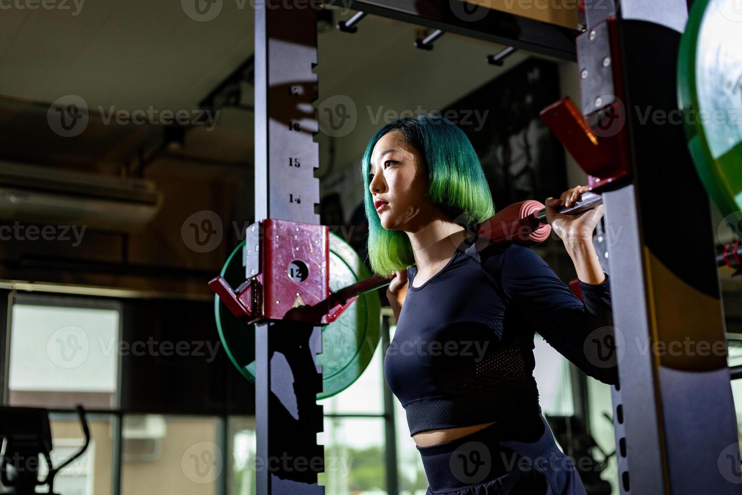 Asian muscular sport woman is practice weight training on deadlift barbell for core muscle inside gym with dark background for exercising and workout photo
